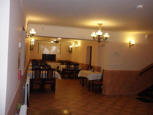 a dining room with tables and chairs and a television at Penzion Pulčínské Skály in Pulčín