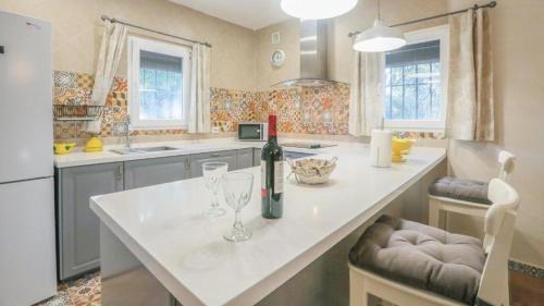 a kitchen with a white counter with a bottle of wine at Casa Rural “La Julianita” in Castaño de Robledo