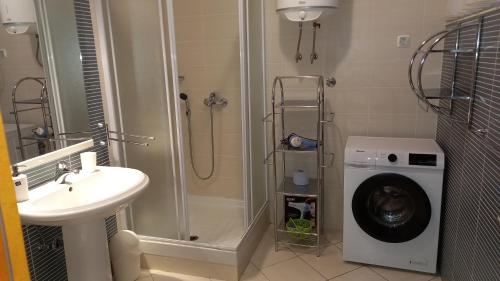 a bathroom with a shower and a sink and a washing machine at Modern Apartment Selce in Selce