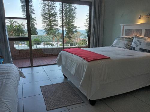 a bedroom with a large bed and a large window at Rockview Guest House in Port Edward