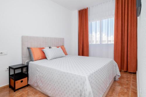 1 dormitorio con cama blanca y cortina naranja en Espanatour SAN JULIAN 41, en Torrevieja