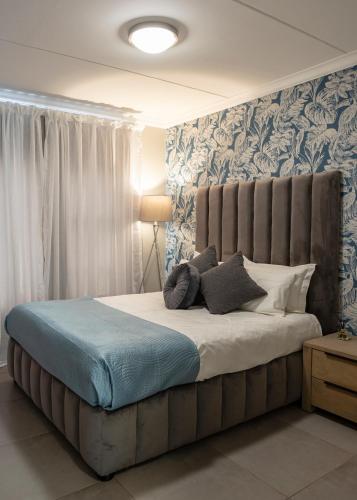 a bedroom with a large bed with blue and white wallpaper at Fore's Luxurious Home in Midrand