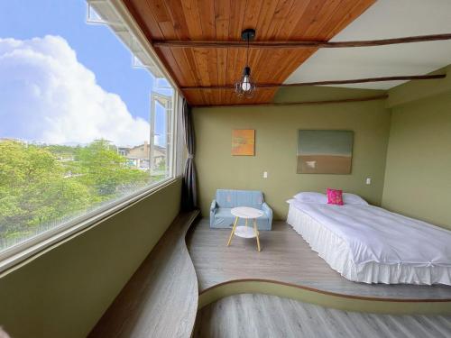 1 dormitorio con cama y ventana grande en 田中歐寒集b&b en Dongshan