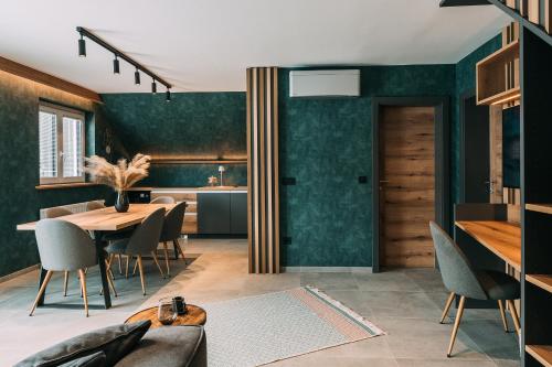 ein Esszimmer mit grünen Wänden sowie einem Tisch und Stühlen in der Unterkunft Guest House Pohorska Kavarna in Maribor