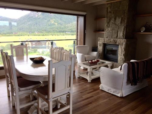 sala de estar con mesa, sillas y chimenea en Arelauquen , Terrazas del Polo en San Carlos de Bariloche