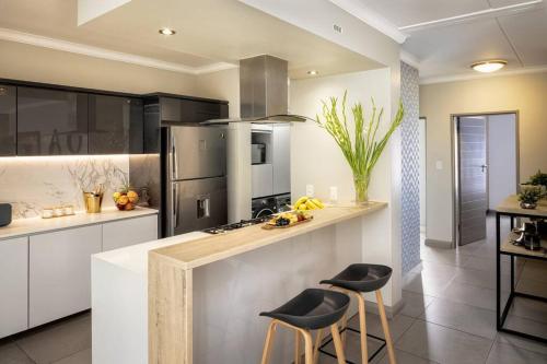 una cocina con una encimera con dos taburetes. en Fore's Luxurious Home, en Midrand