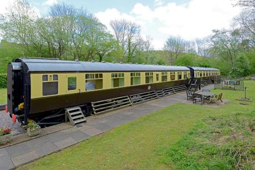 a yellow and black train parked in a park at Carriage 1 - Coalport Station Holidays in Telford