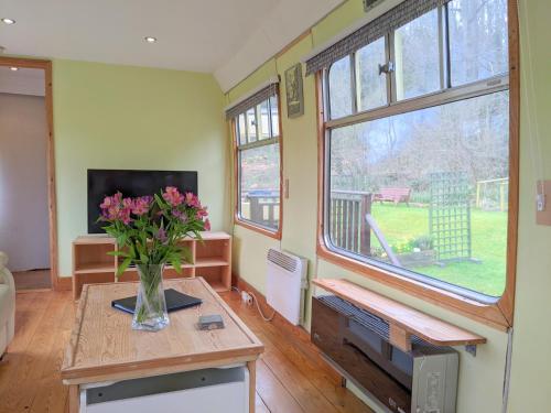 a living room with a vase of flowers on a table at Carriage 1 - Coalport Station Holidays in Telford