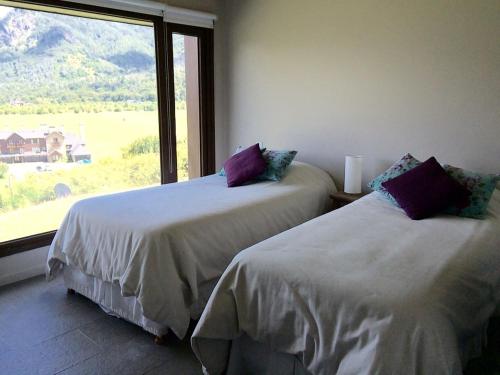 two beds in a room with a large window at Arelauquen , Terrazas del Polo in San Carlos de Bariloche