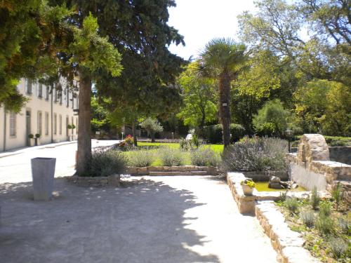 a park with trees and plants and a building at Logis Hôtel Château De Palaja in Carcassonne
