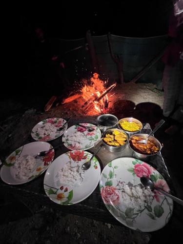 un tavolo con piatti di cibo accanto al fuoco di The woodswalk Treks and tours a Pahalgam