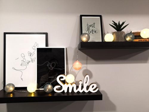 a shelf with two pictures and a sign that says smile at Apartman Jela in Nova Varoš