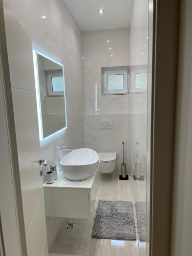 a white bathroom with a sink and a toilet at Two Palms in Duće