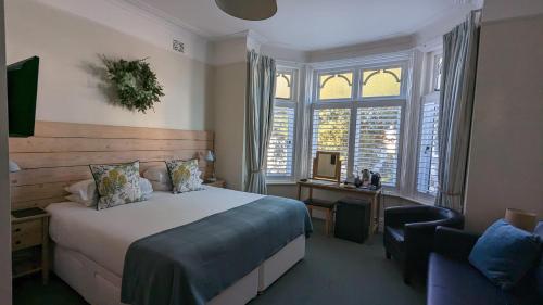 a bedroom with a bed and a chair and windows at Beach Lodge in Bournemouth