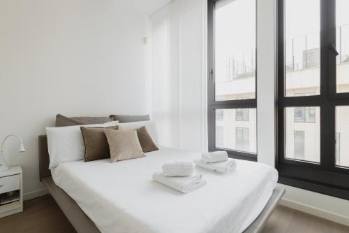 uma cama branca num quarto branco com janelas em Easylife - Lussuosa dimora con rooftop vista Duomo em Milão
