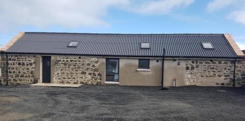 a stone building with a roof on top of it at Country Views The Barn in Dunseverick