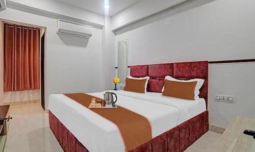 a bedroom with a large bed with a red headboard at FabHotel Elite Residency in Indore