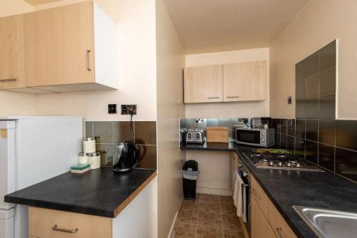 a kitchen with white cabinets and a black counter top at Barden Moor in Darlington