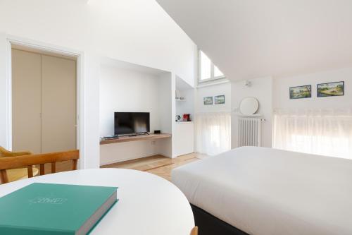 a white bedroom with a bed and a television at Spiga 46 Suites by Brera Apartments in Milan