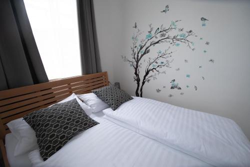 1 cama con sábanas blancas y almohadas con un árbol en la pared en Ferienhaus Scheer, en Retz