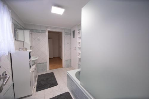 La salle de bains blanche est pourvue d'une baignoire et d'un lavabo. dans l'établissement Ferienhaus Scheer, à Retz