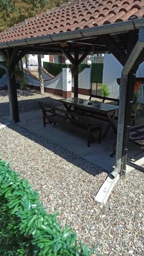 a picnic table and a bench under a pavilion at Apartman Palić Libero in Palić