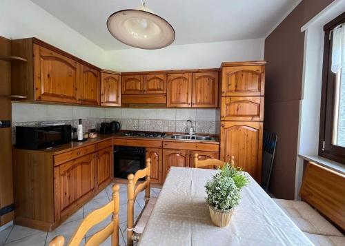 una cocina con armarios de madera y una mesa con una planta en La Casa Di Sabi, en Locana