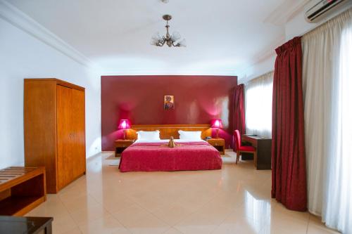 ein Schlafzimmer mit einem großen Bett mit einer roten Wand in der Unterkunft Le Feto in Dakar