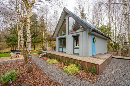 a tiny house in the woods with a wooden porch at Brzozowy Domek in Jarosławiec
