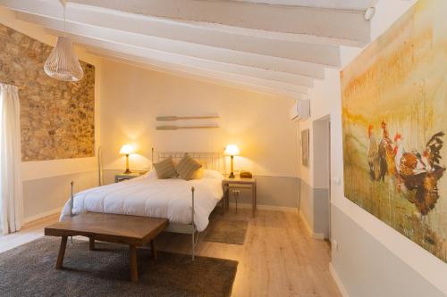 カイマリにあるPintor - Rustic Mallorquin town house 3 bedrooms and pool in Caimariのベッドルーム1室(ベッド1台付)が備わります。壁には絵画が飾られています。
