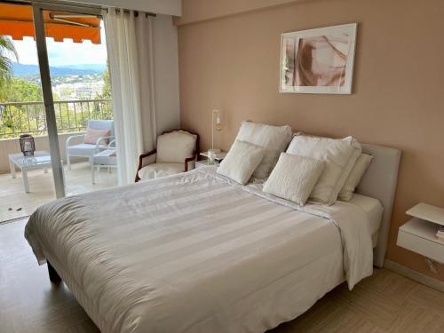 sypialnia z dużym białym łóżkiem i balkonem w obiekcie Au calme, dans la verdure, vue panoramique sur Cannes w mieście Le Cannet