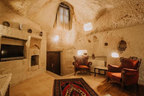 a living room with a couch and chairs and a tv at Village Cave House Hotel in Goreme