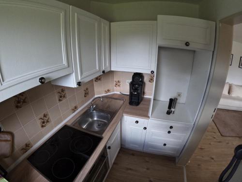 una pequeña cocina con armarios blancos y fregadero en J&J Apartment en Wutöschingen