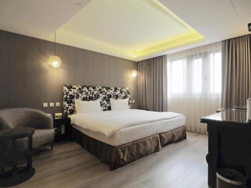 a hotel room with a bed and a chair at Stay Hotel - Taichung Yizhong in Taichung