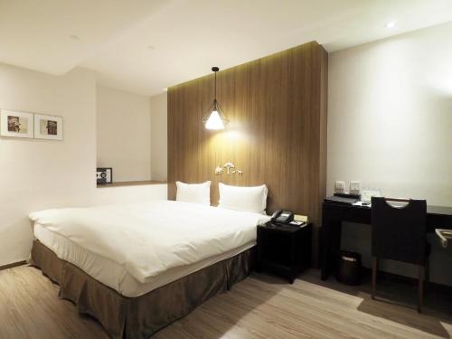 a hotel room with a large bed and a desk at Stay Hotel - Taichung Yizhong in Taichung