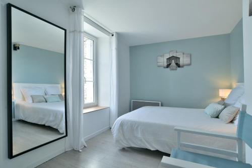 Dormitorio blanco con espejo y cama en Ty Karet - Maison pour 6 proche plage, en Saint-Cast-le-Guildo
