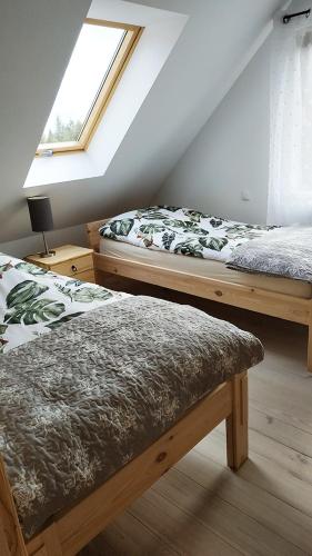 a attic room with two beds and a window at Chata Krusznia in Giby