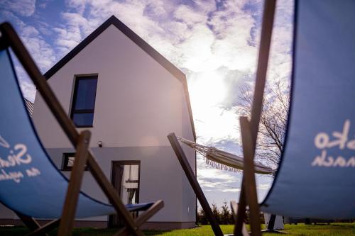 ein weißes Haus mit der Sonne im Hintergrund in der Unterkunft Siedlisko na wydmach, sauna,podgrzewane jacuzzi,domki klimatyzowane,starlink internet,parking in Łeba
