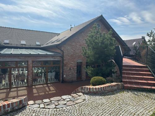 ein Backsteingebäude mit einer Terrasse und einem Baum in der Unterkunft Krzewi Róg in Garcz