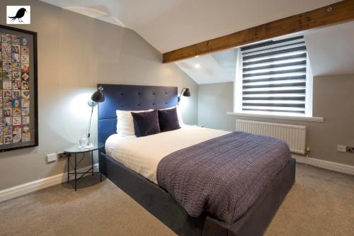 a bedroom with a bed with a blue headboard and a window at Blackbird Luxury Apartments Room 4 in Blackpool