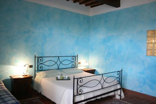 a blue bedroom with a bed and two night tables at Villa Il Poggiarone in Montepulciano