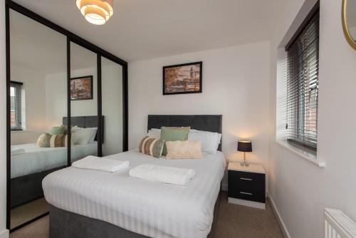 a white bedroom with two beds and a mirror at Grange Way in Bowburn