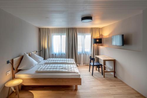 a bedroom with a bed and a desk in it at Gasthof Löwen Tosters in Feldkirch
