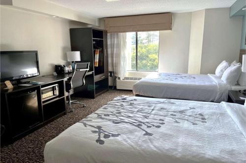 Habitación de hotel con 2 camas y TV de pantalla plana. en Caper House Inn en Augusta