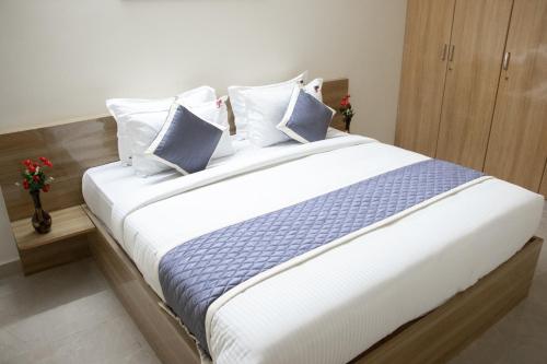 ein Schlafzimmer mit einem großen Bett mit blauen und weißen Kissen in der Unterkunft Richinn Palace home stay in Chennai