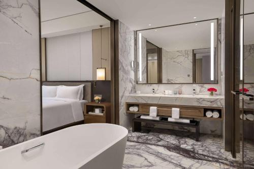 een badkamer met een bad, een bed en een spiegel bij Wyndham Grand Lishui Downtown & Poetry Hotel in Lishui