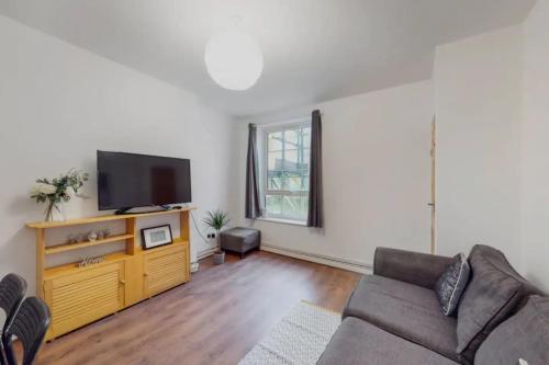 a living room with a couch and a flat screen tv at Central & Cosy 2BD Flat near Canary Wharf in London