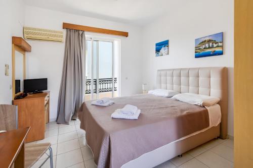 una camera da letto con un grande letto con asciugamani di Johnhara Studios & Apartments a Ialyssos