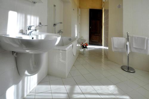 a white bathroom with a sink and a tub at Zamek Cerveny Hradek in Jirkov