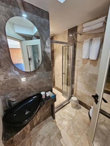 baño con bañera negra y espejo en Anthemis Hotel, en Estambul